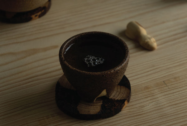 Qué es el té y qué es Ankori, copa para té con licor dentro y una mascota de té hecha de madera.